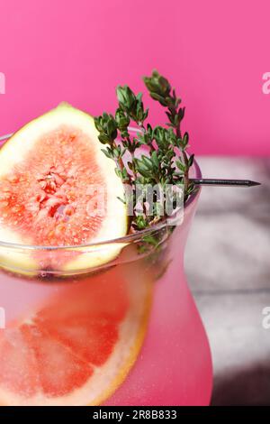 Fresh summer cocktail with fig, grapefruit and thyme near pink wall Stock Photo