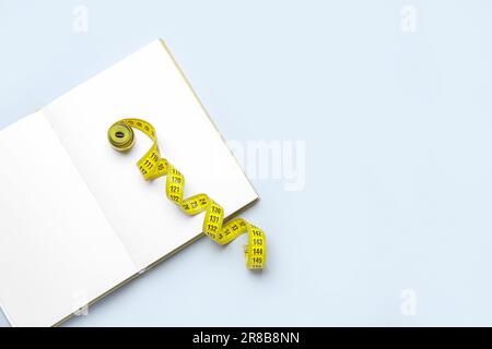 Blank open notebook and measuring tape on light background Stock Photo