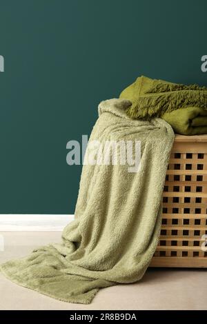 New soft blankets on basket near green wall Stock Photo