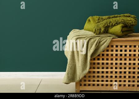 New soft blankets on basket near green wall Stock Photo