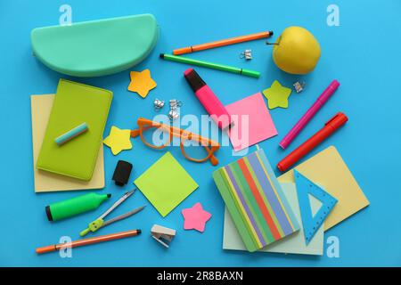 Stylish eyeglasses with apple and different stationery on blue background Stock Photo
