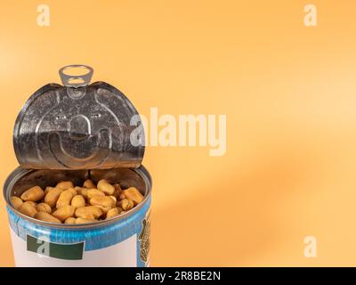 Roasted peanuts in an open jar on orange. Peanuts close up. Stock Photo