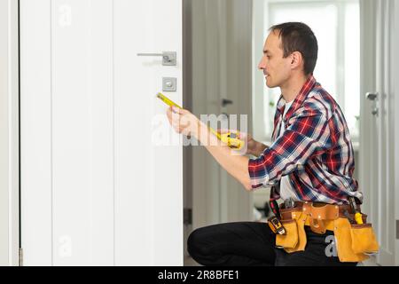 Master with screwdriver installs door hinges. Stock Photo