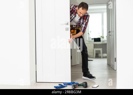 Master with screwdriver installs door hinges. Stock Photo