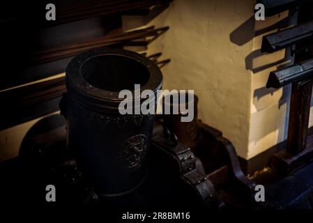 An closeup of an old-fashioned smoking pipe resting on a wall, surrounded by various tools Stock Photo