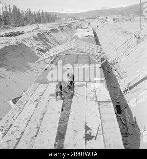 Current 14-1950: Jernverket in Mo i Rana.Well over 800 men are in the process of erecting the Iron Works in Mo i Rana, and the work is progressing rapidly. Booming mine shots, oxygen pounding from compression drills and massive rock masses the air to tremble and quiver, and down in the mountain the tunnels criss-cross their way. Much has been done, but much remains to be done.  This concrete-cast giant grave goes by the name 'the duct'. In it, the cables from the transformer stations run inside the mountain, as well as two large water pipes. Under the 'duct' the main sewer is buried. The 'duct Stock Photo