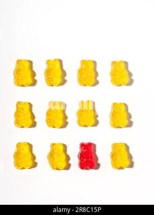 One red gummy bear among yellow gummy bears. Creative concept. Stock Photo