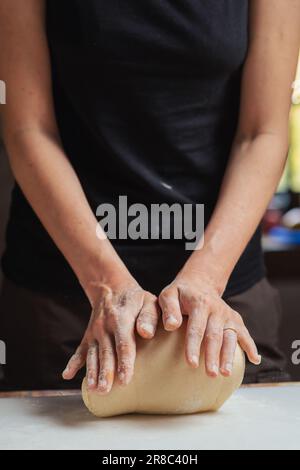 Unrecognizable woman prepares dough on cutting board. Preparation of dough for bread, pizza. Stock Photo