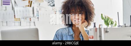African-American dressmaker draws watching online lesson via laptop in light studio Stock Photo