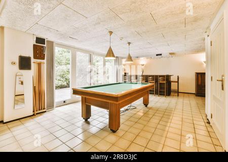 a pool room with a pool table and billiard in the center of the room is an open door that leads to a patio Stock Photo