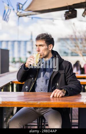 Man drinking a lemonade while sitting in a bar at the harbor Stock Photo