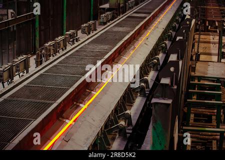 Rolled metal factory hot steel bar moving on conveyor. Stock Photo