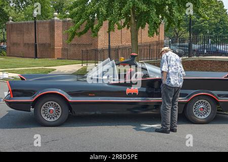 A visitor views a replica Batmobile from the 1960s television show. Dover Comic Con, Dover, Delaware USA 2023. Stock Photo