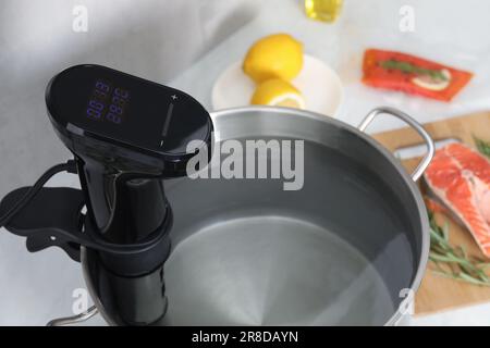 Sous vide cooker in pot on white table, closeup. Thermal immersion circulator Stock Photo