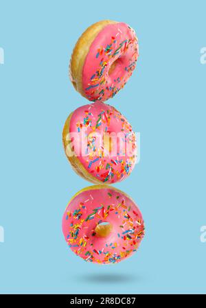 Tasty donuts with sprinkles on light blue background Stock Photo