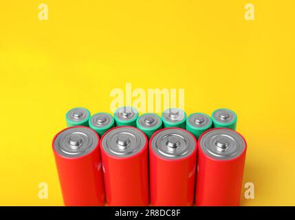 Batteries of different sizes on yellow background. Space for text Stock Photo