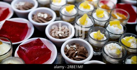 Dessert buffet catering concept. Selective focus dessert on buffet counter. Dessert in plate, cup, and glass on table at restaurant for lunch buffet. Stock Photo