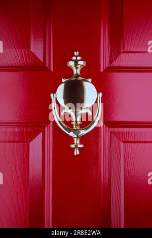 Close-up of old fashioned brass door knocker on red front door Stock Photo