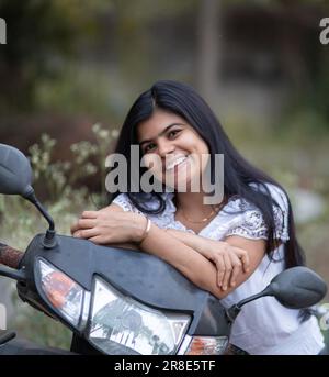 An Indian beautiful young girl with scooter smiling and having fun Stock Photo