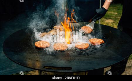 Preparing juicy beef hamburger patties . BBQ meat sizzling over hot flames. Stock Photo