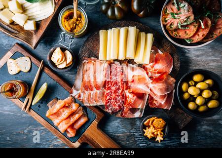 Appetizers with different antipasti, charcuterie, snacks, meat platter with cheese and spicy olives, salmon carpaccio and tomato salad Stock Photo