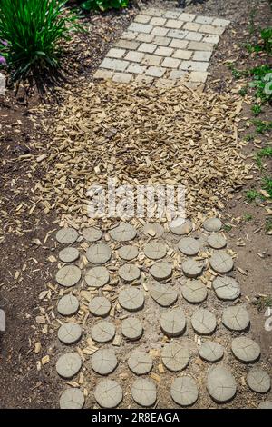 Garden path made of natural wooden planks, stones,  gravel. Healthy sensory path with different surfaces. Stock Photo