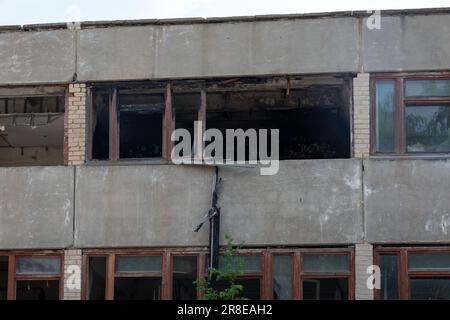 Broken windows in the facade of an old building after an accident, earthquake, disaster, war. Broken glass, a hole in the glass of an office building Stock Photo