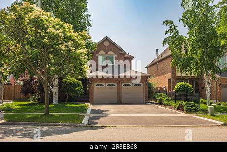 Real Estate Exterior Front House on a sunny day. Big custom made luxury houses with nicely landscaped front yard and driveway to garage in summer in t Stock Photo