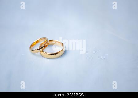 Golden wedding rings for engagement. Marriage golden rings with white, pink ribbons background. Rings on the white and red rose. The marriage rings is Stock Photo