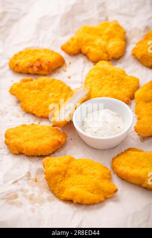 Small chicken schnitzel on baking sheet with herb mayonnaise Stock Photo
