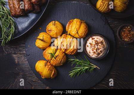 Hasselback potatoes (potato fans) with additional herbs, spices and whipped feta dip Stock Photo