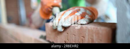 Bricklayer lays bricks on cement building exterior or interior walls Stock Photo