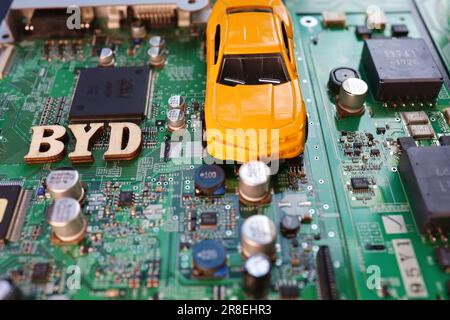 Motherboard and yellow minicar. Image photo of BYD's automobiles and semiconductors. Stock Photo
