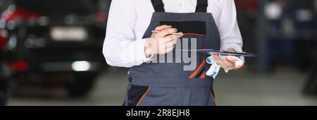 Auto mechanic holding clipboard and pen in car service. Service and repair auto concept Stock Photo