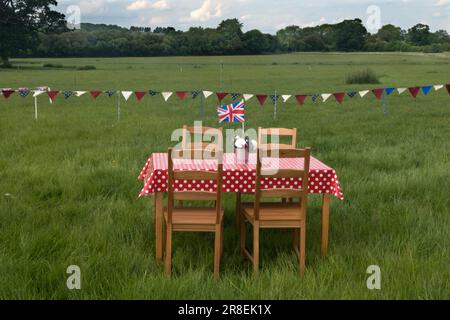 Picnic table in a field Union Jack flag, bunting. Queen Elizabeth II Platinum Jubilee celebrations. Villagers prepare for a communal evening meal to mark the Queen's 70 years on the throne. Theddingworth, Leicestershire, England 2nd June 2022. 2020s UK HOMER SYKES Stock Photo