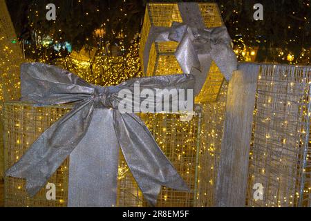 great gifts under the city Christmas tree at night glow garlands Stock Photo