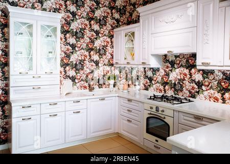 white classic style kitchen, floral peony print wallpaper, interior, kitchen furniture. St. Petersburg, Russia - 05.29.23 Stock Photo