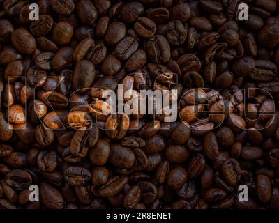 A heap of coffee beans is featured in this image, with the words 'Organic' and 'Whole' highlighted Stock Photo