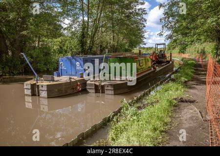 Workboats on a canal in Worcestershire, one carrying an excavator prepare to carry out essential works along the waterway. Canal & River Trust. Stock Photo