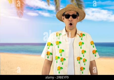 Latin man on vacation wearing floral shirt hat sunglasses at tropical beach afraid and shocked with surprise expression, fear and excited face. Stock Photo