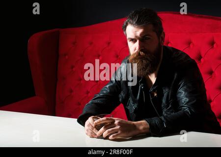 Elegant and stylish man in classical wear with wiskey. Cheerful bearded sman is drinking expensive whisky. Old traditional whiskey drink - gentlemans Stock Photo