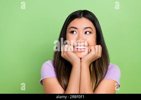 Photo of pretty vietnamese chinese young girl look empty space admire dressed stylish violet outfit isolated on green color background Stock Photo