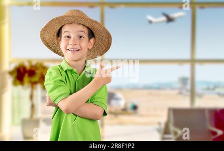Litel boy at airport smiling and looking at the camera pointing with two hands and fingers to the side and copy space Stock Photo