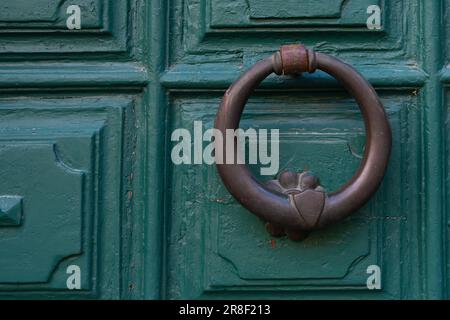 Old bronze ring door knocker on a green painted wooden portal Stock Photo