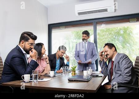 Stress situation in conference room, indian boss unhappy with the performance of his employees for doing doing bad work. Stock Photo