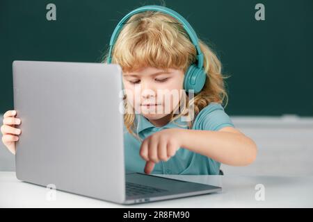 Cute boy wearing headphones, study with laptop in classroom, listening ...