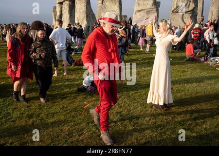 Spiritually-minded revellers celebrate the summer Solstice (mid-summer and longest day) at the ancient late-Neolithic stones of Stonehenge, on 21st June 2023, in Wiltshire, England. The summer solstice is the northern hemisphere's longest day and shortest night of the year, when the earth’s axis is tilted at its closest point from the sun and pagans say the ancient monument is a sacred place that links the Earth, Moon, Sun and the seasons. Stonehenge was built in three phases between 3,000 B.C. and 1,600 B.C. Stonehenge is owned by English Heritage who say 8,000 visitors were allowed into the Stock Photo