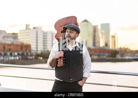 Portrait of a musician looking away while holding his guitar on his shoulder Stock Photo