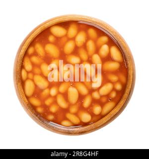 Canned baked beans in tomato sauce, in a wooden bowl. A dish, containing white beans, cooked through a steam process. Convenience food. Stock Photo