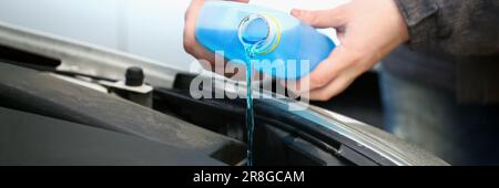 Pouring blue antifreeze liquid for washing car glass closeup Stock Photo